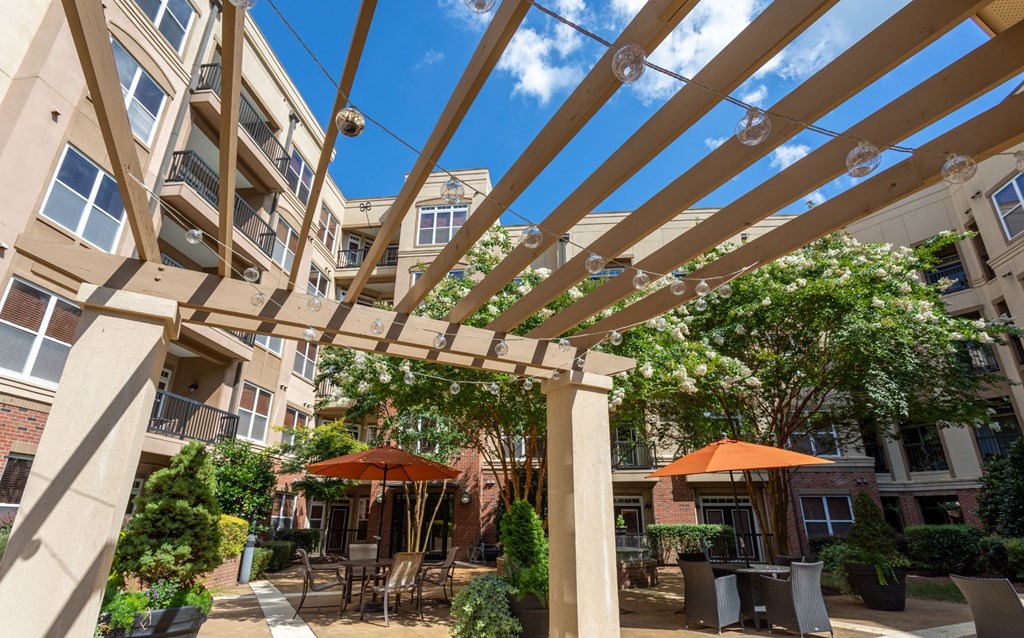 A patio with tables and chairs under a pergola.