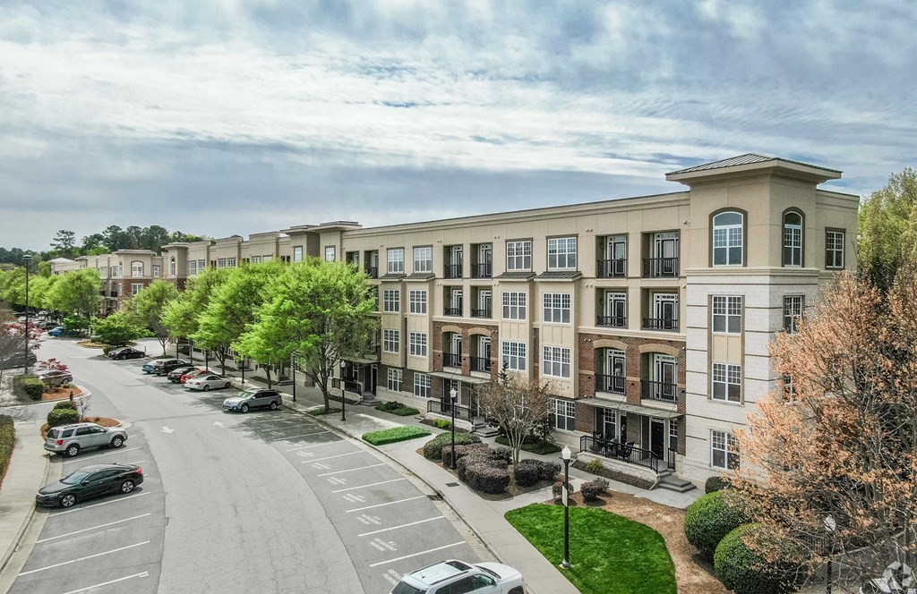 A street view of a row of apartment buildings with cars parked on the side of the road.