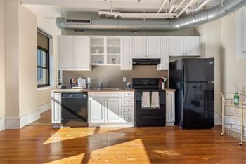 A kitchen with black appliances and white cabinets.