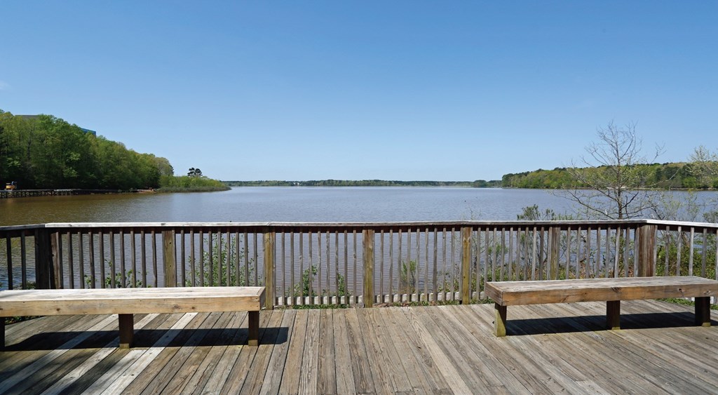 A wooden deck overlooks a body of water with benches on either side.