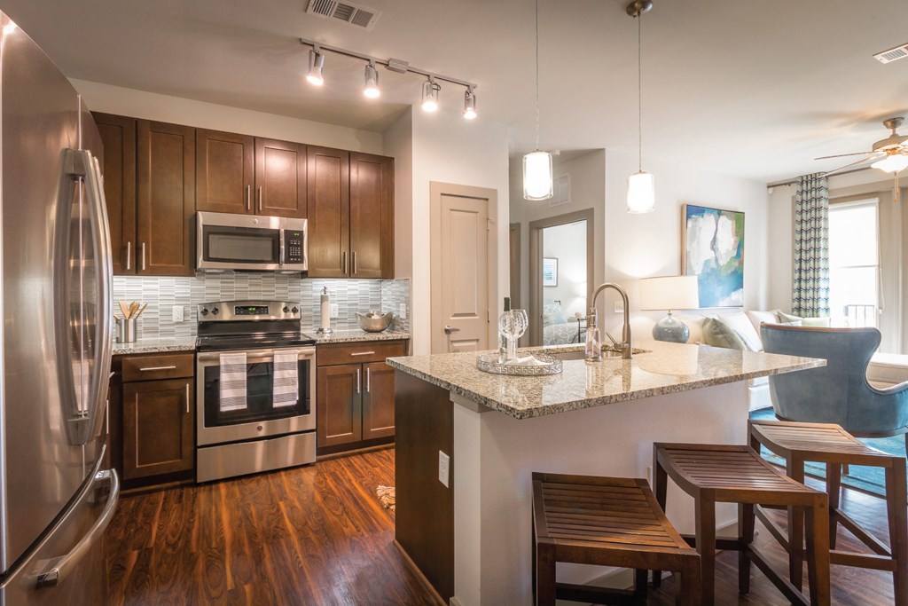 A modern kitchen with wooden cabinets and a granite countertop.