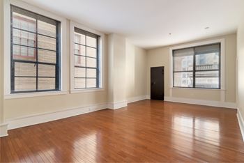 A room with wooden floors and three windows.