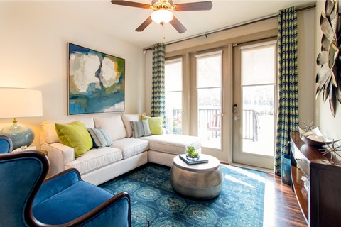 A living room with a white couch, a blue chair, and a painting on the wall.