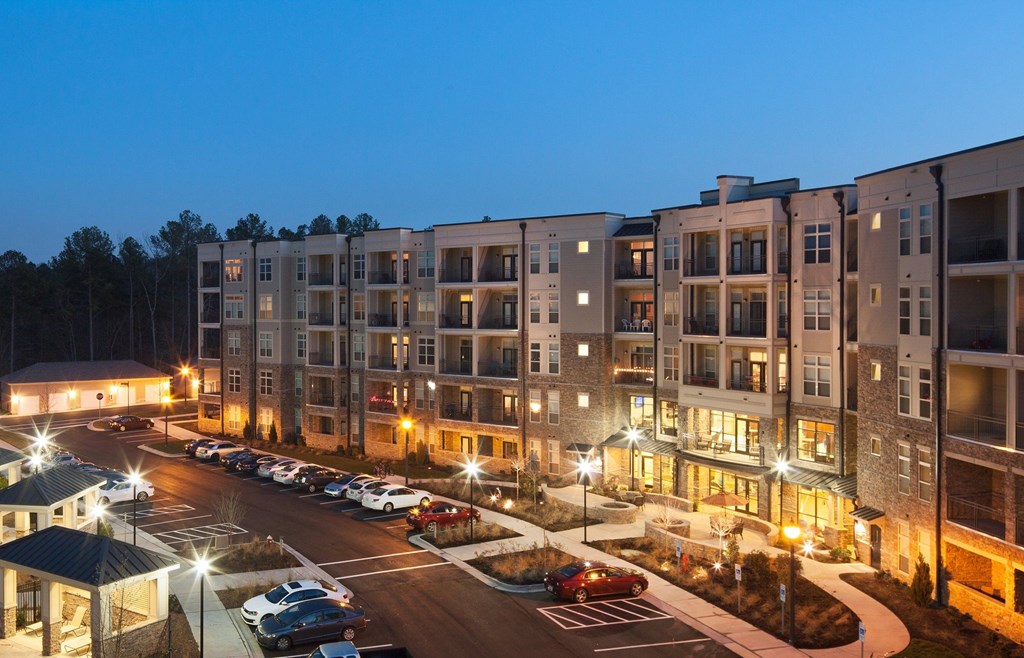 A parking lot in front of a building with cars parked.