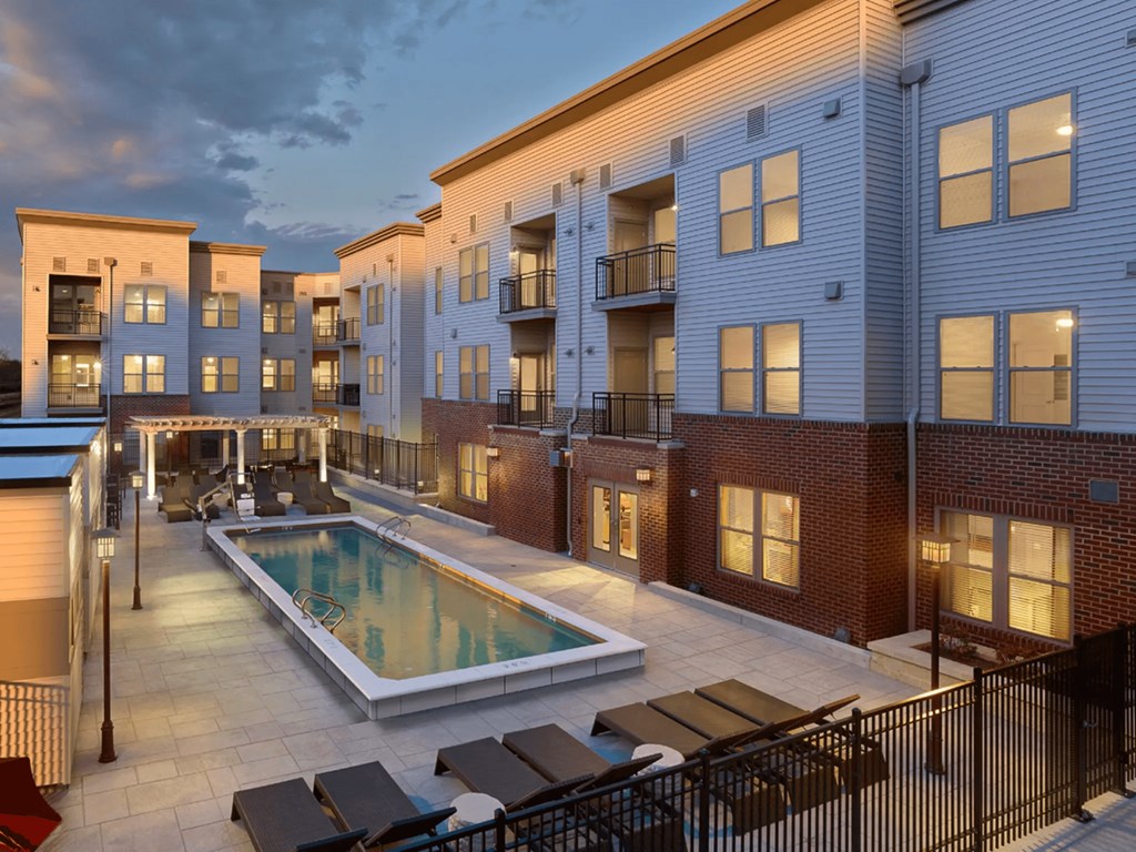 A pool surrounded by patio furniture and a black fence.