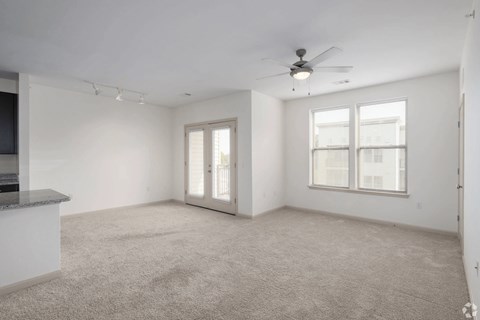 A spacious living room with a ceiling fan and carpeted floor.