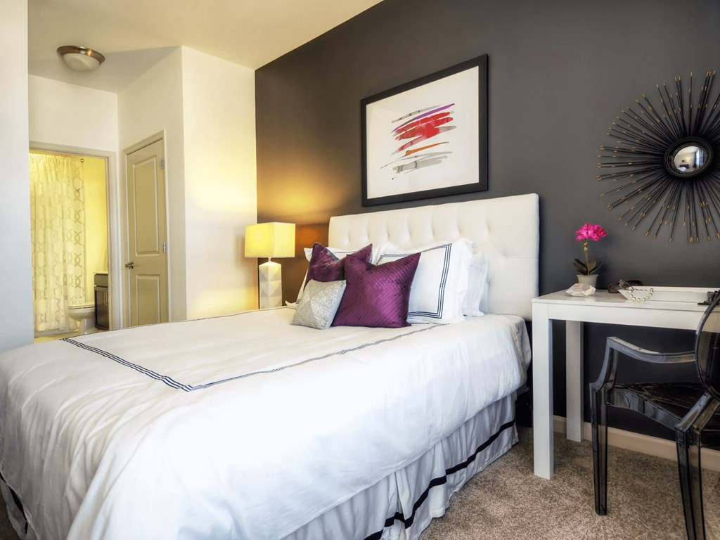 A bedroom with a white bed and a black chair.