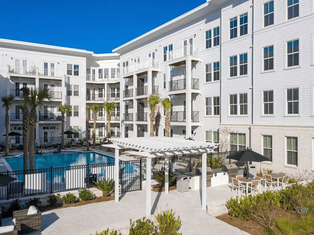 A white apartment building with a pool in the courtyard.