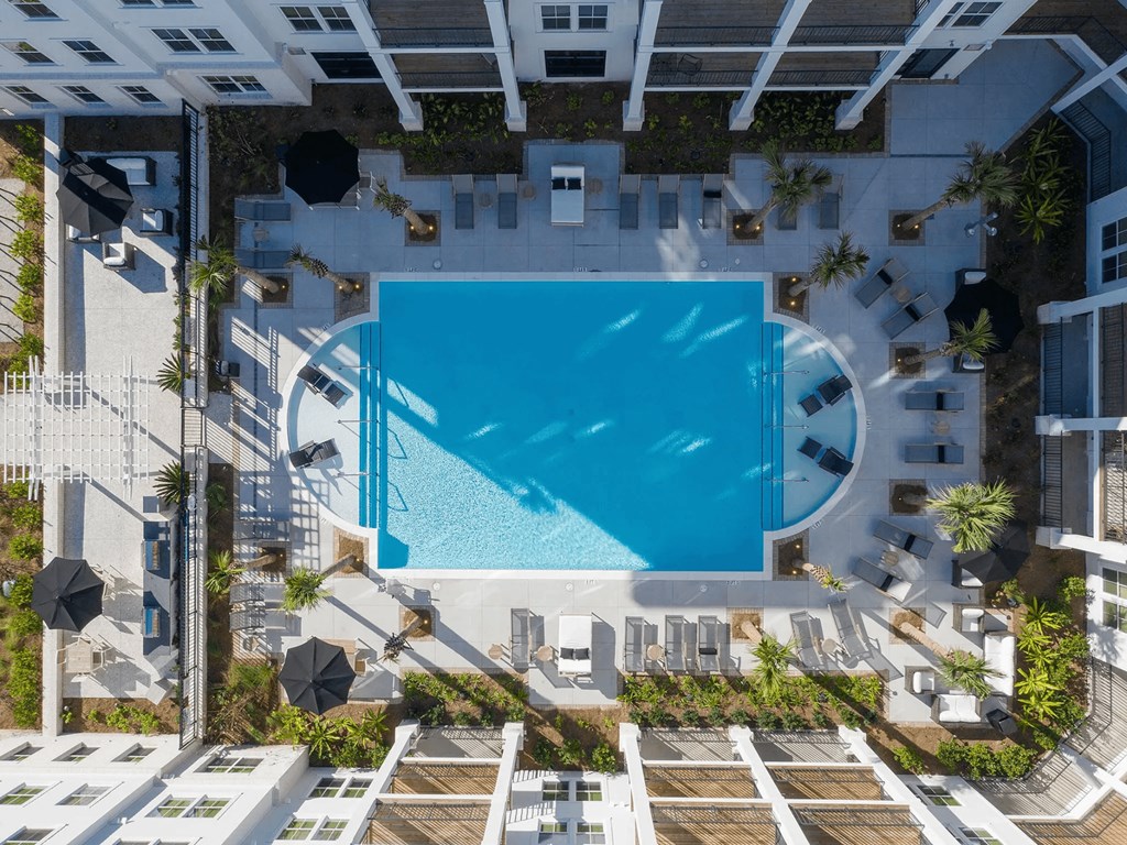 A swimming pool surrounded by lounge chairs and umbrellas.