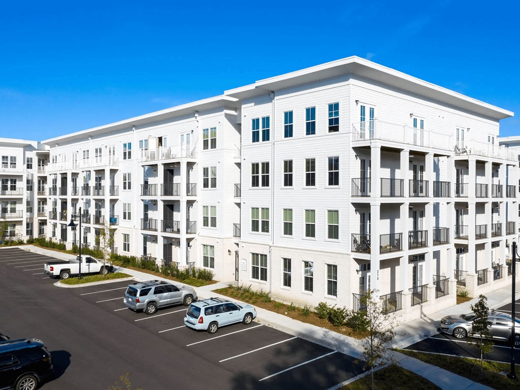 A white apartment building with cars parked in the parking lot.