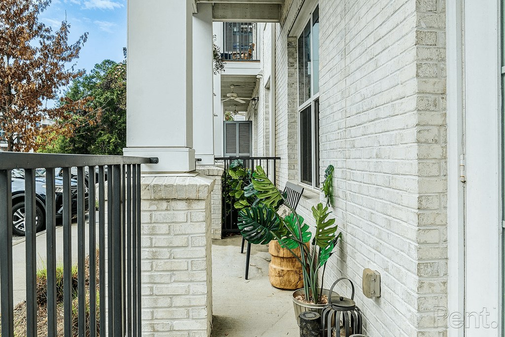 A white house with a black gate and plants on the porch.