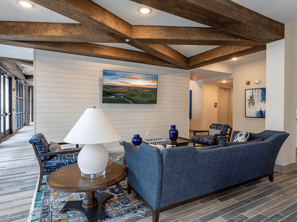A living room with a blue couch and a painting on the wall.