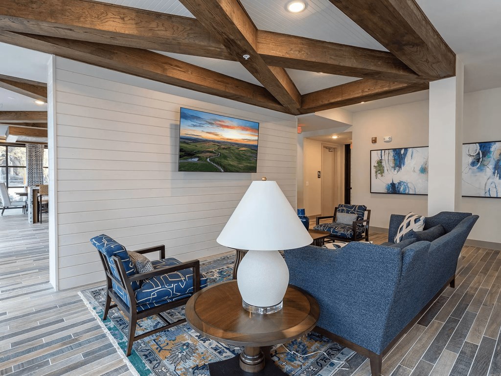 A living room with a blue couch, a wooden table, and a painting on the wall.