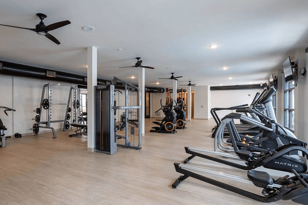 A gym with a variety of equipment including treadmills, weights, and exercise bikes.