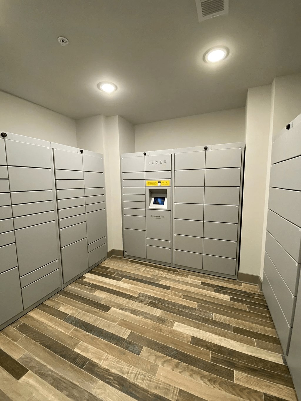 A room with a wood floor and a wall of lockers.