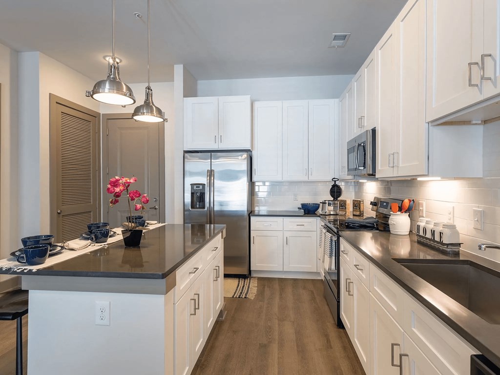 A kitchen with white cabinets and a black countertop.