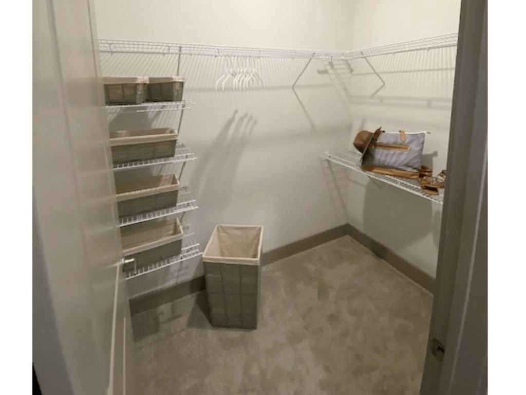 A small, empty walk-in freezer with a single shelf and a plastic bin on the floor.