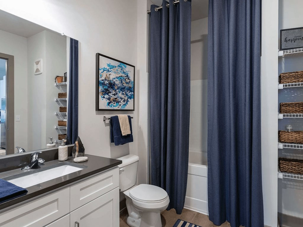 A bathroom with a toilet, sink, and blue curtains.