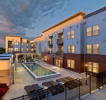 A modern apartment complex with a pool in the courtyard.