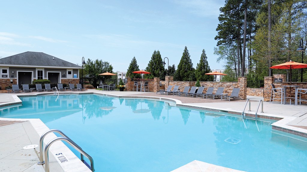A large swimming pool with a metal ladder and a small building in the background.