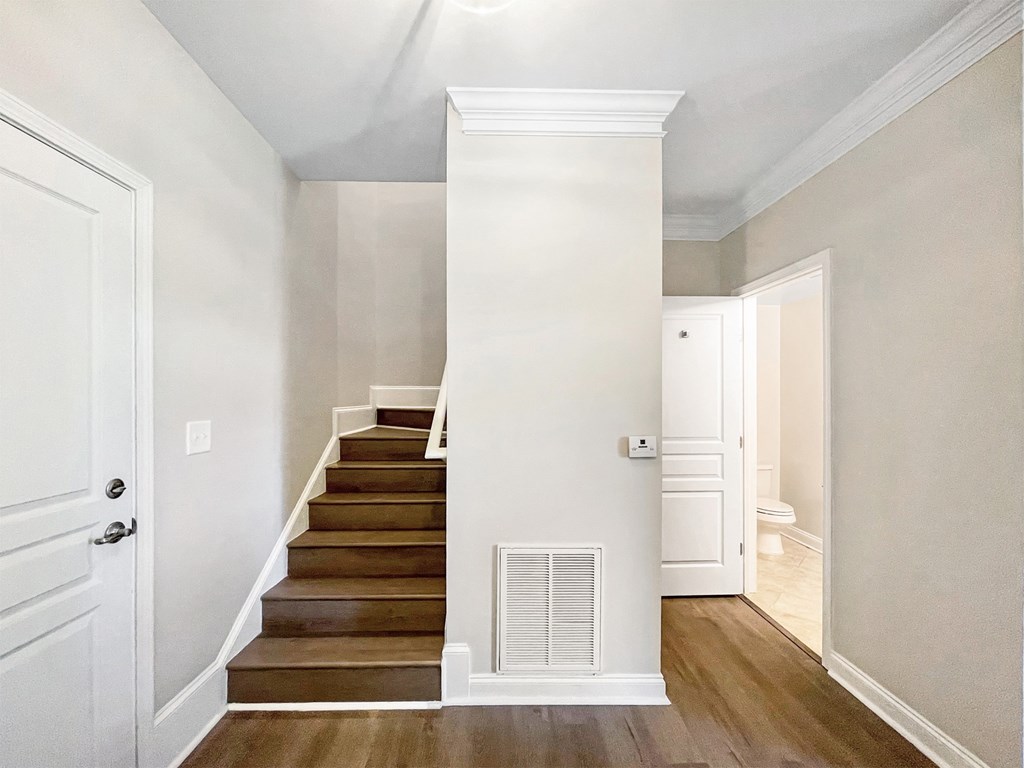 A white door is on the left of a staircase with a white column.