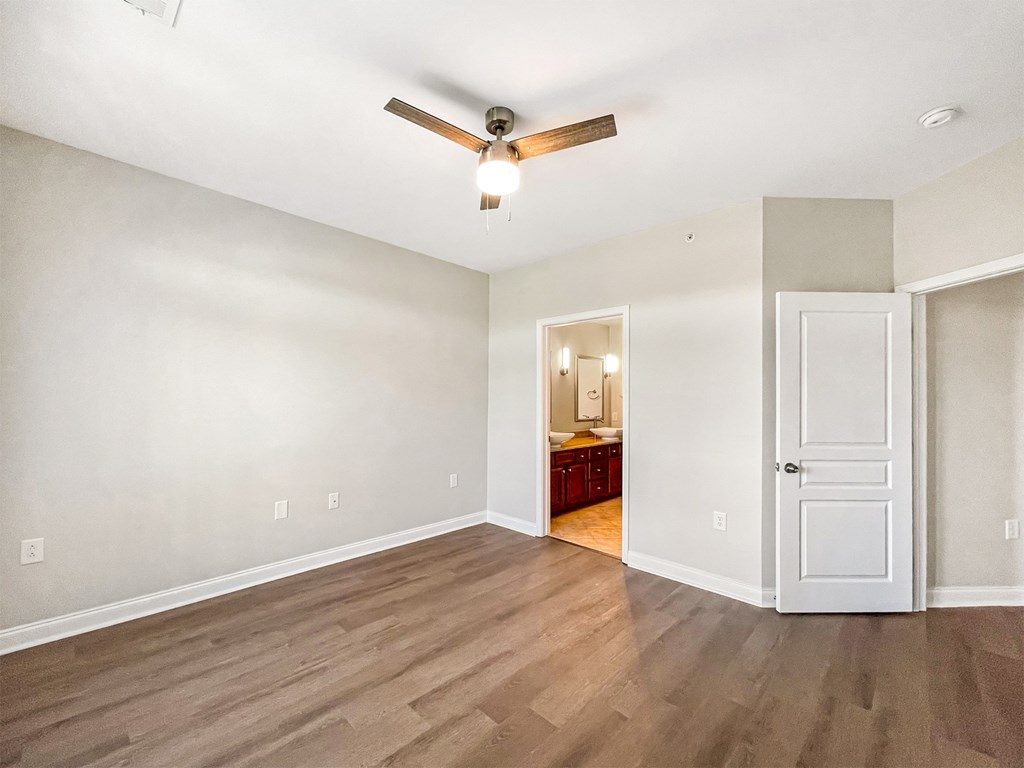 A room with a ceiling fan and wooden flooring.