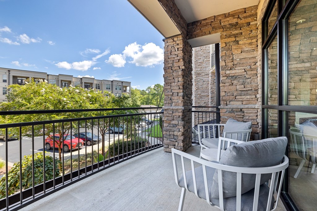 A balcony with a grey sofa and a stone pillar.