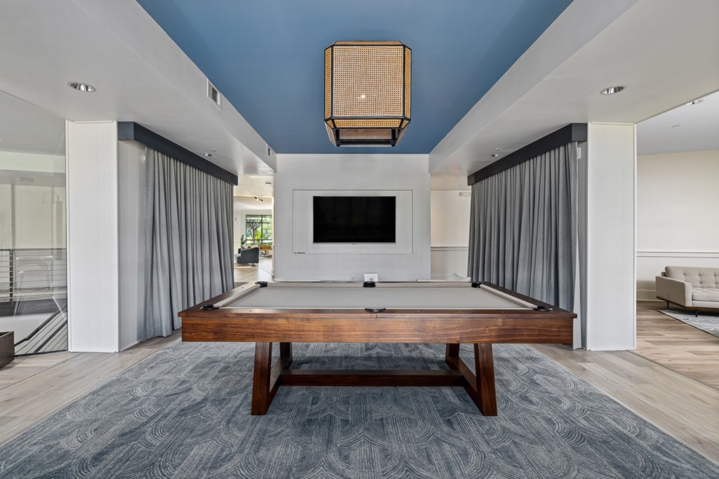 A billiard table is in the middle of a room with a television.