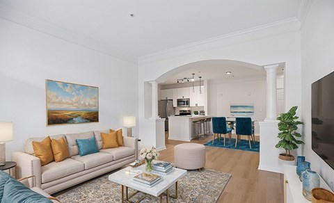 A living room with a beige couch, a coffee table, and a painting on the wall.