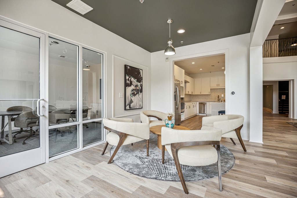 A modern dining room with a glass door leading to a kitchen.