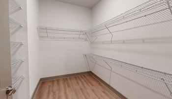 A walk-in closet with wooden floors and metal wire shelving.