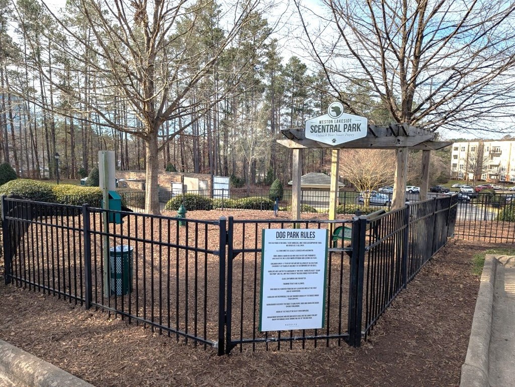 A sign in front of a fence that says Dog Park Rules.