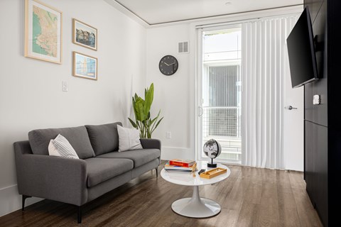 A grey couch with two pillows sits in a living room with a white coffee table in front of it.