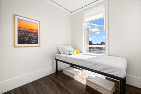 A bedroom with a bed, nightstand, and a picture on the wall.