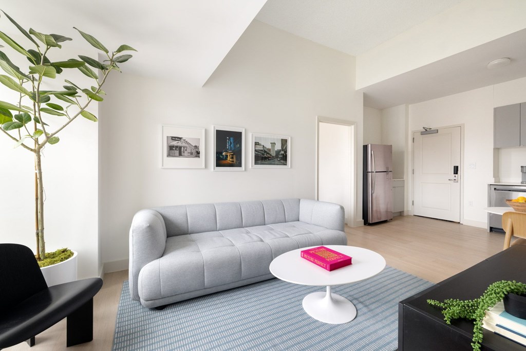 A living room with a grey couch and a red book on a white table.