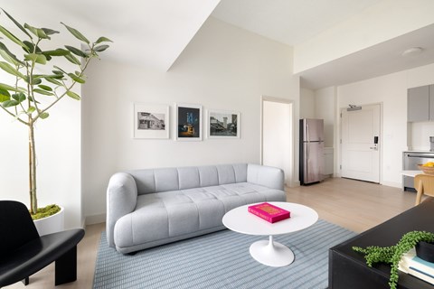 A living room with a grey couch and a red book on a white table.