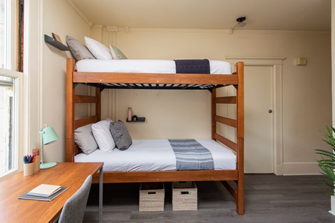 A bedroom with a bunk bed and a desk.