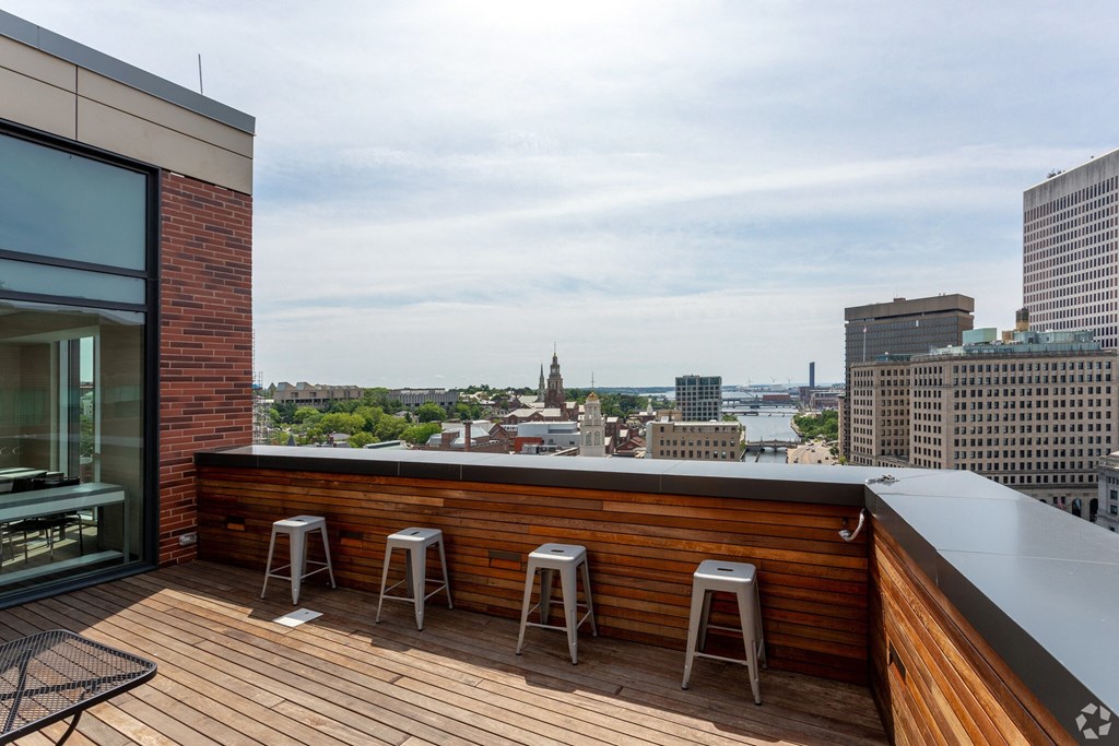 a balcony with a view of the city and a deck with bar stools