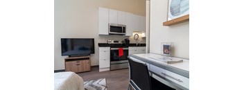 a kitchen with white cabinets and black and white appliances and a table and chairs