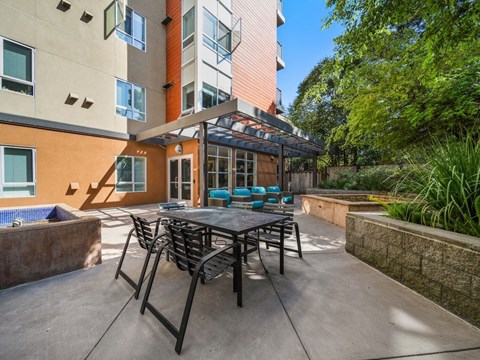 A patio with a table and chairs is surrounded by a wall and trees.