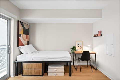 A bedroom with a bed, desk, and chair.