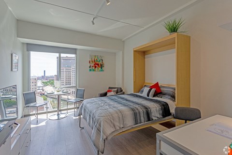 A bedroom with a large bed and a balcony overlooking the city.