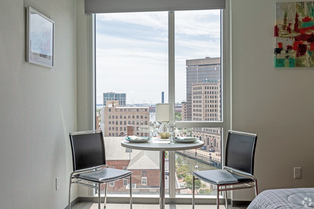 a small table with two chairs in front of a window with a city view