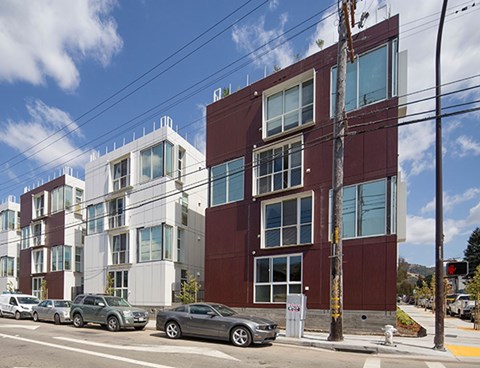 A row of modern buildings with cars parked in front.