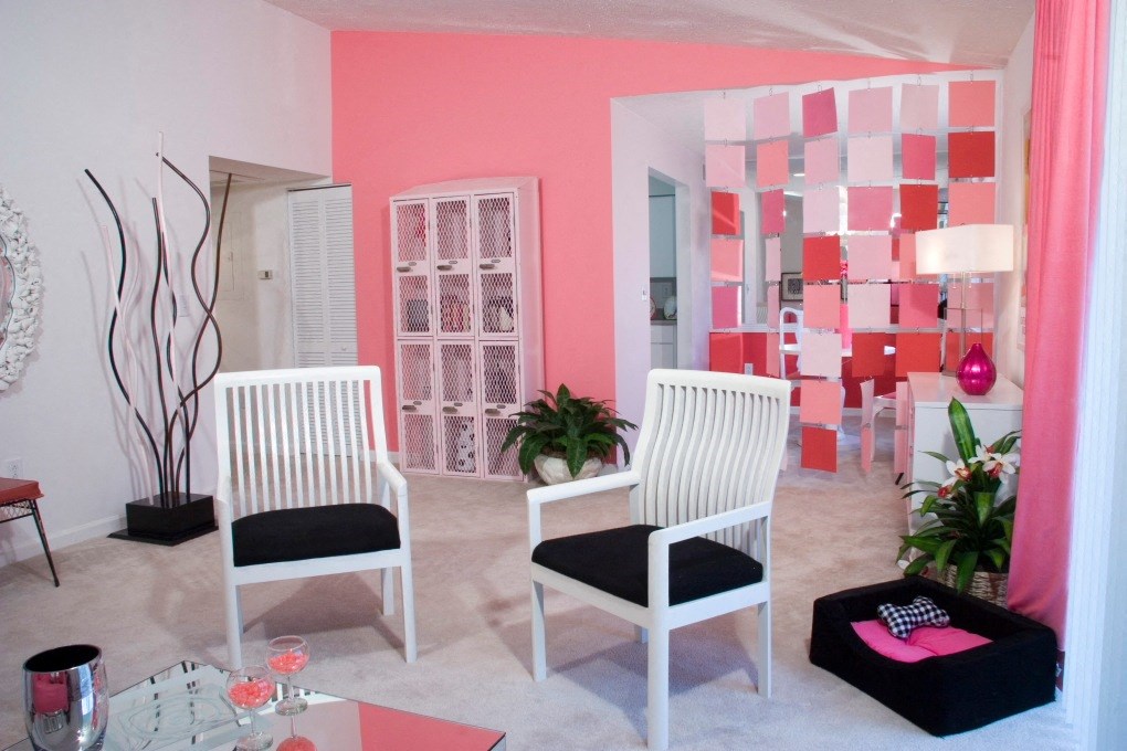 a living room with two white chairs and a pink wall