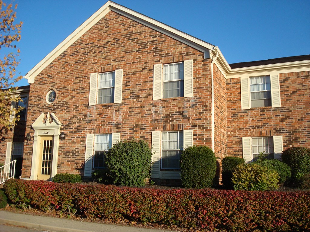 the front of a brick house with a blue sky in the background