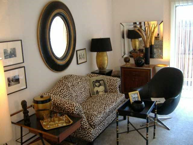 a living room with a leopard print couch and a mirror