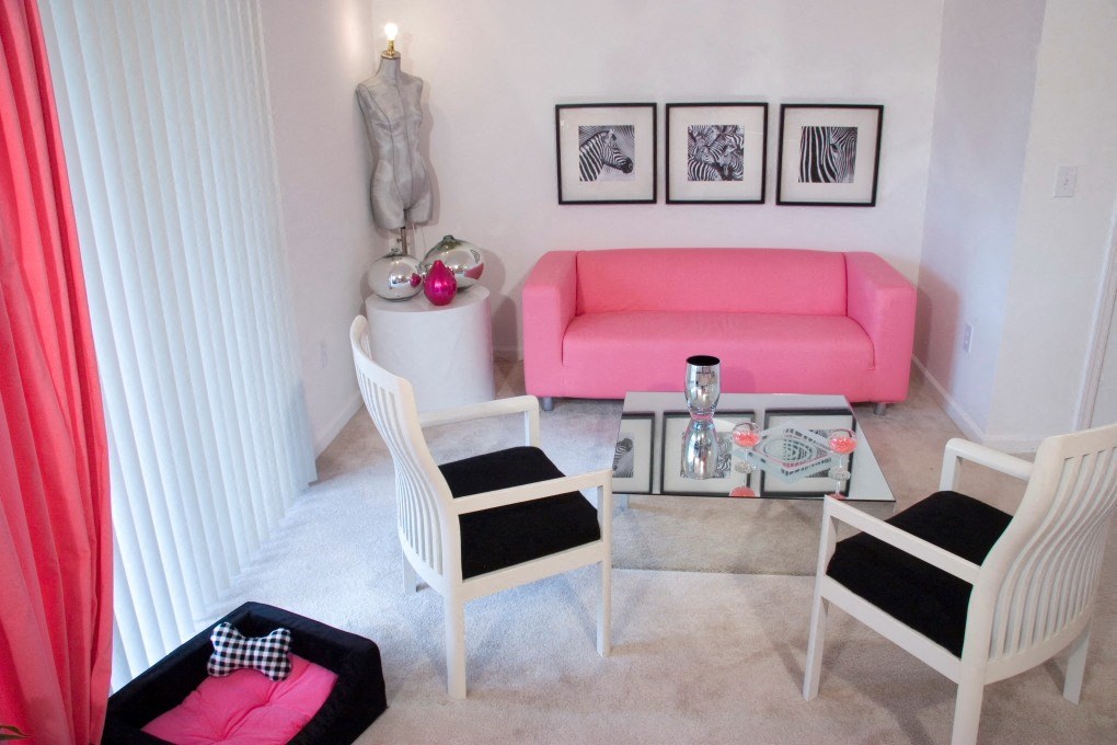 a living room with a pink couch and a table and chairs