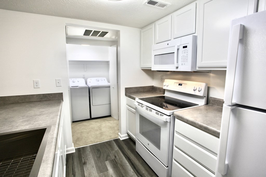 a kitchen with white cabinets and appliances and a white refrigerator