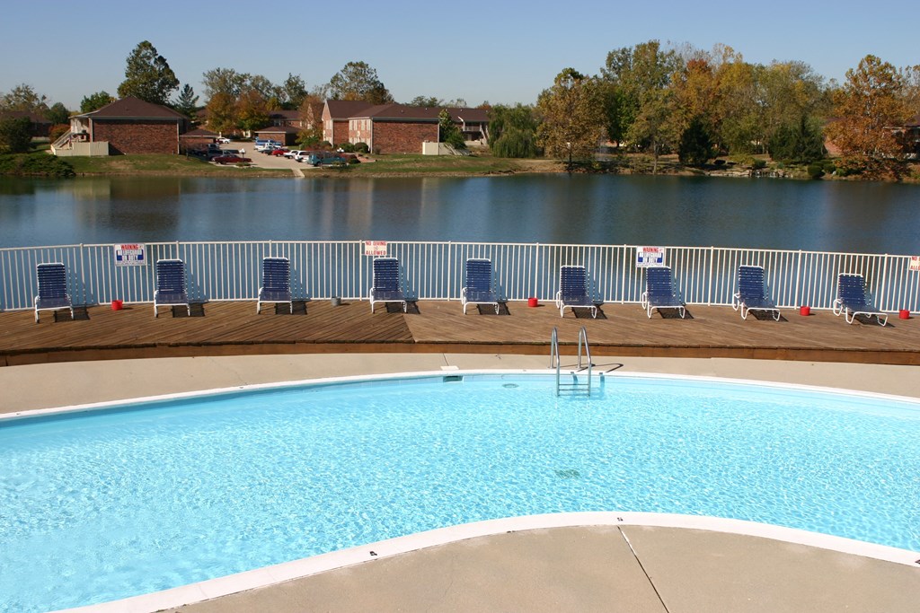 a swimming pool with blue chairs next to a body of water
